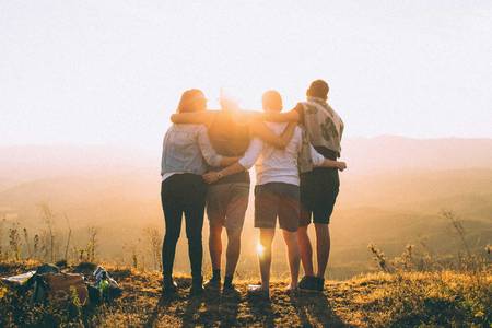 Quelle: unsplash.com / Helena Lopes, https://unsplash.com/de/@wildlittlethingsphoto 4er Gruppe umarmt sich und schaut in die Ferne
